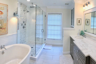 Example of a mid-sized beach style master white tile and subway tile porcelain tile, gray floor and double-sink bathroom design in Cincinnati with beaded inset cabinets, gray cabinets, a two-piece toilet, white walls, an undermount sink, marble countertops, a hinged shower door, white countertops and a built-in vanity
