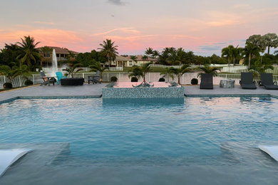 Hot tub - large modern backyard custom-shaped natural hot tub idea in Miami with decking