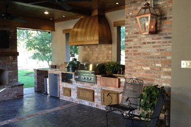 Large mountain style backyard stamped concrete patio kitchen photo in New Orleans with a roof extension