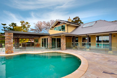 Inspiration for a mid-sized country backyard custom-shaped pool in Other with concrete pavers.