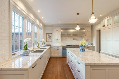 Large elegant u-shaped medium tone wood floor and brown floor enclosed kitchen photo in Other with a single-bowl sink, beaded inset cabinets, white cabinets, marble countertops, white backsplash, subway tile backsplash, paneled appliances, an island and white countertops