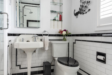 Photo of a mid-sized traditional master bathroom in Providence with a two-piece toilet, subway tile, a pedestal sink, white floor, a hinged shower door, black and white tile, white walls and mosaic tile floors.