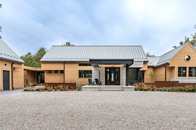 Trendy brown one-story wood and clapboard exterior home photo in Other with a metal roof and a gray roof