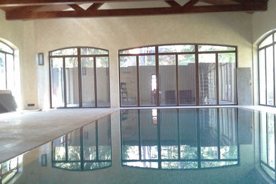 Foto de piscina alargada clásica grande interior y rectangular con adoquines de piedra natural