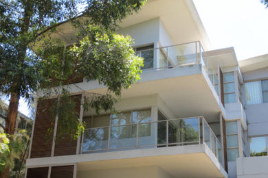 Large contemporary three-storey brick white apartment exterior in Sydney with a flat roof and a metal roof.