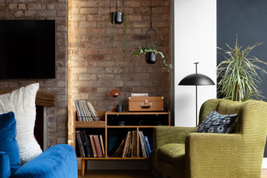 Design ideas for a large midcentury open plan living room in Manchester with white walls, light hardwood flooring, a wood burning stove, a wooden fireplace surround, a wall mounted tv, brick walls and a chimney breast.