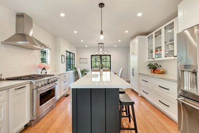 Inspiration for a small transitional galley light wood floor eat-in kitchen remodel in San Francisco with an undermount sink, shaker cabinets, white cabinets, concrete countertops, white backsplash, ceramic backsplash, stainless steel appliances, an island and gray countertops