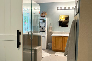 Inspiration for a mid-sized transitional master gray tile and ceramic tile ceramic tile, gray floor and double-sink bathroom remodel in Denver with raised-panel cabinets, medium tone wood cabinets, a two-piece toilet, blue walls, an undermount sink, solid surface countertops, a hinged shower door, white countertops and a built-in vanity