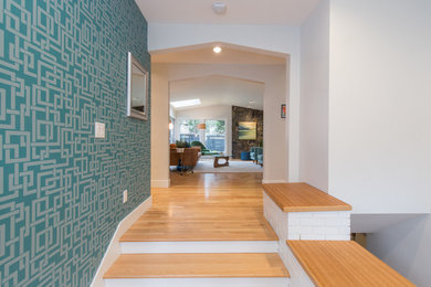 Example of a mid-sized mid-century modern light wood floor and beige floor entryway design in Other with white walls and a medium wood front door