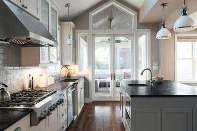 Example of a mid-sized minimalist single-wall dark wood floor open concept kitchen design in DC Metro with a farmhouse sink, recessed-panel cabinets, gray cabinets, soapstone countertops, gray backsplash, subway tile backsplash, stainless steel appliances and an island