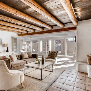 Mittelgroßes, Fernseherloses, Abgetrenntes Mediterranes Wohnzimmer mit weißer Wandfarbe, Terrakottaboden, Kamin, Kaminsims aus Beton und beigem Boden in Sonstige