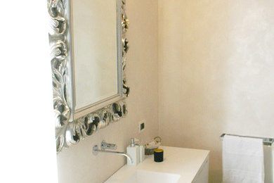 Ispirazione per una stanza da bagno bohémian con ante bianche, WC sospeso, pareti beige e lavabo integrato