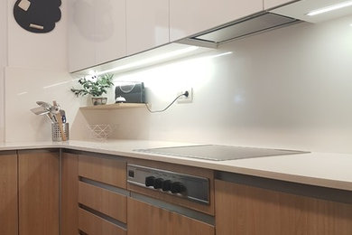 バルセロナにあるお手頃価格の小さなモダンスタイルのおしゃれなキッチン (一体型シンク、フラットパネル扉のキャビネット、白いキャビネット、クオーツストーンカウンター、白いキッチンパネル、大理石のキッチンパネル、シルバーの調理設備、磁器タイルの床、アイランドなし、黒い床) の写真