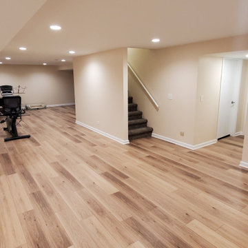 Fully remodeled 1970s finished basement with luxury vinyl plank flooring and can
