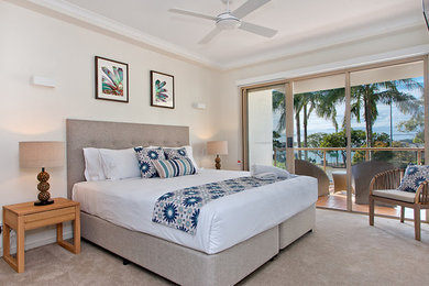 Design ideas for a mid-sized beach style master bedroom in Sunshine Coast with white walls, carpet and brown floor.