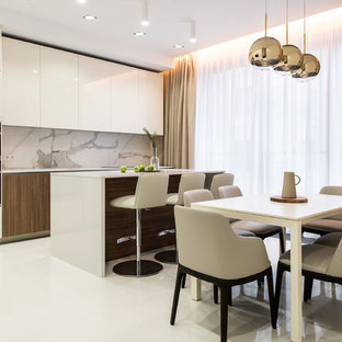 Новые идеи обустройства дома: линейная кухня в современном стиле с плоскими фасадами, белыми фасадами, серым фартуком, черной техникой, островом, белым полом и белой столешницей