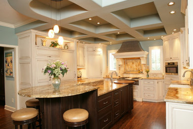 Example of a large classic u-shaped dark wood floor and brown floor eat-in kitchen design in Kansas City with a farmhouse sink, raised-panel cabinets, beige backsplash, an island, beige cabinets, granite countertops and ceramic backsplash