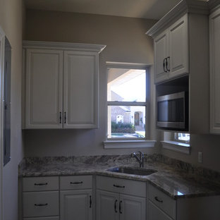 ニューオリンズの中サイズのトロピカルスタイルのおしゃれなランドリールーム (アンダーカウンターシンク、レイズドパネル扉のキャビネット、白いキャビネット、御影石カウンター、ベージュの壁、磁器タイルの床、左右配置の洗濯機・乾燥機) の写真