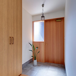 他の地域の片開きドアコンテンポラリースタイルのおしゃれな玄関 (白い壁、コンクリートの床、木目調のドア、グレーの床) の写真