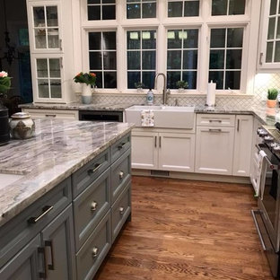 Aménagement d'une grande arrière-cuisine classique en L avec un évier de ferme, un placard avec porte à panneau encastré, des portes de placard blanches, un plan de travail en granite, une crédence blanche, une crédence en carreau de porcelaine, un électroménager en acier inoxydable, un sol en bois brun, un îlot central et un plan de travail bleu.