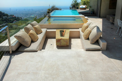 Mid-sized minimalist backyard stone patio photo in Los Angeles with a fire pit and a roof extension