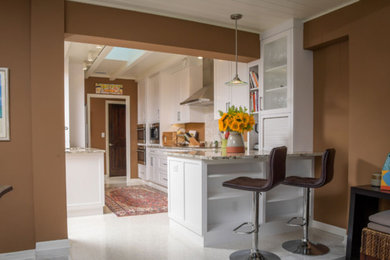 Inspiration for a mid-sized transitional galley white floor enclosed kitchen remodel in Miami with shaker cabinets, white cabinets, granite countertops, stainless steel appliances, a peninsula, an undermount sink, white backsplash, mosaic tile backsplash and multicolored countertops