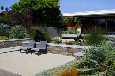 Diseño de jardín de secano marinero en patio trasero con exposición total al sol y adoquines de hormigón