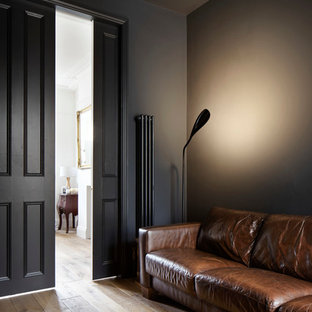 Foto di un piccolo soggiorno minimal chiuso con libreria, pareti nere, parquet scuro, nessun camino e parete attrezzata