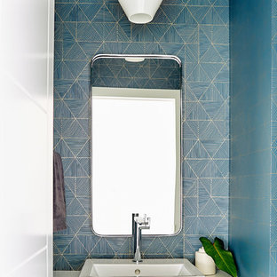 Diseño de aseo actual con encimera de cuarzo compacto, paredes azules, lavabo sobreencimera y encimeras blancas