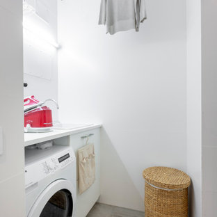 Diseño de cuarto de lavado lineal, contemporáneo, pequeño, con armarios con paneles lisos, puertas de armario blancas, encimera de laminado, paredes blancas, suelo de baldosas de cerámica, suelo gris, encimeras blancas y fregadero encastrado
