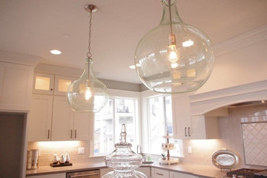 Example of a large trendy l-shaped open concept kitchen design in Portland with an undermount sink, shaker cabinets, white cabinets, gray backsplash, ceramic backsplash, stainless steel appliances and an island