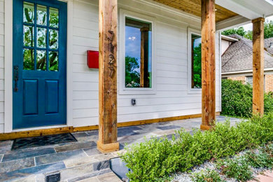 This is an example of a mid-sized farmhouse stone front porch design in Dallas with a roof extension.