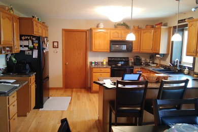 Eat-in kitchen - large transitional u-shaped light wood floor and multicolored floor eat-in kitchen idea in Cedar Rapids with an undermount sink, raised-panel cabinets, dark wood cabinets, granite countertops, metallic backsplash, ceramic backsplash, stainless steel appliances, an island and gray countertops