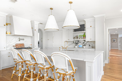 Kitchen - transitional l-shaped medium tone wood floor and brown floor kitchen idea in Atlanta with an undermount sink, recessed-panel cabinets, white cabinets, white backsplash, white appliances, an island and white countertops