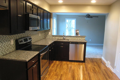Inspiration for a small transitional l-shaped medium tone wood floor enclosed kitchen remodel in Philadelphia with an undermount sink, shaker cabinets, dark wood cabinets, granite countertops, blue backsplash, glass tile backsplash and stainless steel appliances