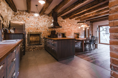 Mittelgroße Urige Wohnküche mit Landhausspüle, Kassettenfronten, dunklen Holzschränken, Arbeitsplatte aus Holz, Rückwand aus Stein, Küchengeräten aus Edelstahl, braunem Holzboden und Halbinsel in Stuttgart