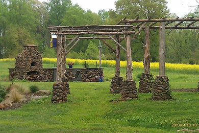 Example of a mid-sized farmhouse backyard gravel patio design in Other with a fire pit and a pergola