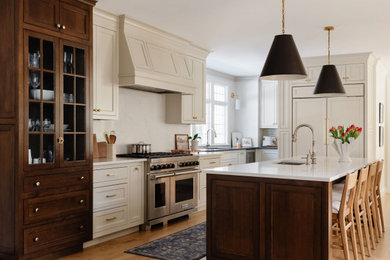 Huge transitional l-shaped light wood floor and beige floor eat-in kitchen photo in Boston with an undermount sink, recessed-panel cabinets, beige cabinets, white backsplash, stone slab backsplash, stainless steel appliances, an island and white countertops