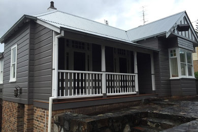 Large industrial two-storey grey house exterior in Wollongong with wood siding, a gable roof and a metal roof.