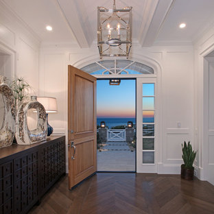 Ispirazione per un ingresso costiero di medie dimensioni con pareti bianche, pavimento in legno massello medio, una porta singola e una porta in legno bruno