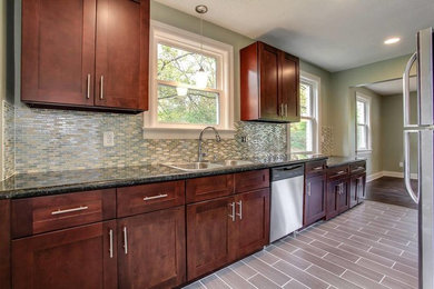 Inspiration for a large transitional galley ceramic tile and gray floor open concept kitchen remodel in Nashville with a drop-in sink, shaker cabinets, dark wood cabinets, granite countertops, beige backsplash, glass tile backsplash, stainless steel appliances and no island