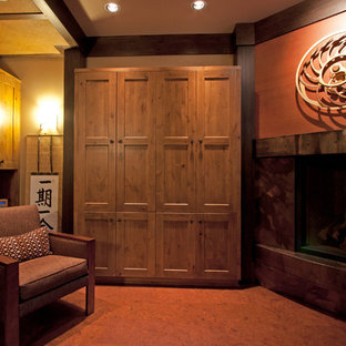 Ejemplo de despacho de estilo zen con suelo de corcho, chimenea de esquina, marco de chimenea de metal y escritorio empotrado