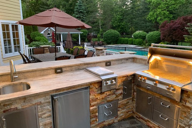 Mid-sized elegant backyard stone patio kitchen photo in New York with no cover