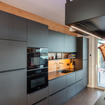 Moderne Küche mit dunklen Fronten und Holz
