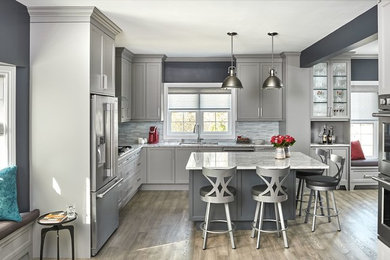 Inspiration for a large contemporary medium tone wood floor and gray floor kitchen remodel in Toronto with gray cabinets, quartz countertops, white backsplash, glass tile backsplash, stainless steel appliances, an island and white countertops
