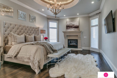 Large transitional master bedroom in Oklahoma City with beige walls, dark hardwood floors, a standard fireplace, a stone fireplace surround and brown floor.
