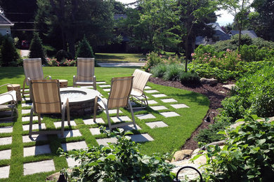 This is an example of a mid-sized traditional partial sun backyard stone landscaping in Providence with a fire pit for summer.