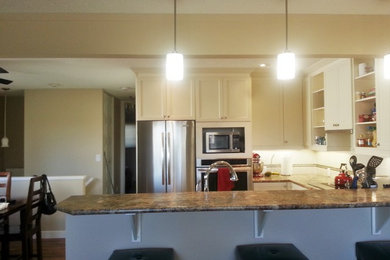 Eat-in kitchen - small transitional u-shaped medium tone wood floor eat-in kitchen idea in Calgary with a drop-in sink, shaker cabinets, white cabinets, laminate countertops, white backsplash, ceramic backsplash, white appliances and a peninsula