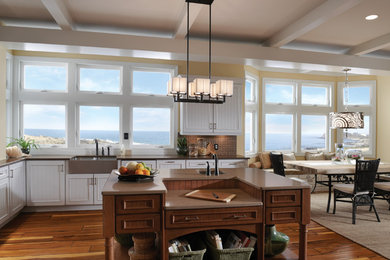 Example of a transitional l-shaped medium tone wood floor open concept kitchen design in San Francisco with a farmhouse sink, recessed-panel cabinets, white cabinets and an island