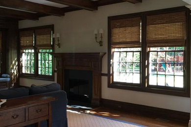 Example of a large classic formal and enclosed dark wood floor living room design in New York with beige walls, a standard fireplace, a wood fireplace surround and a wall-mounted tv